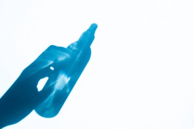 shadow hand holding a spray bottle on a blue background, free space. Cosmetics for face and body