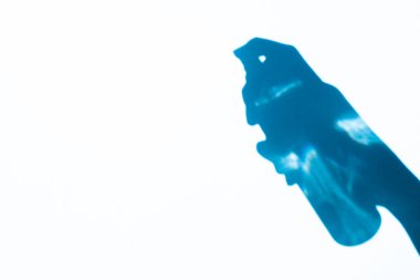shadow hand holding a spray bottle on a blue background, free space. Cosmetics for face and body