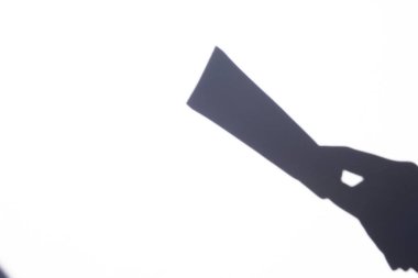 shadow female hand holding a tube of cream on a white background. body and face care