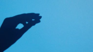 shadow snaps fingers on blue background, free space