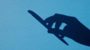 shadow hand twists the handle on a blue background, free space. Sign contract. Sign a document