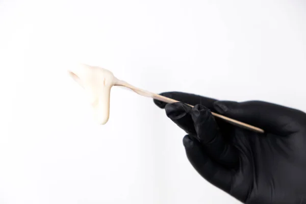 Sugar depilation. A piece of sugar paste dripping from a wooden spatula