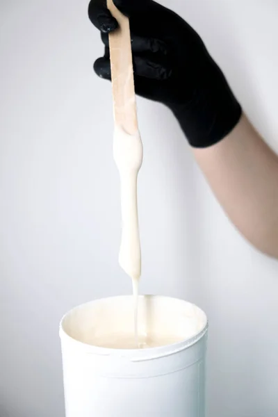 Sugar depilation. Sugar paste dripping from a wooden spatula into a jar