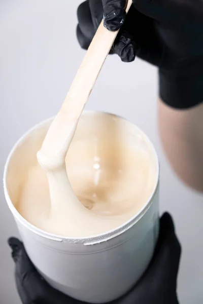 Sugar depilation. Sugar paste dripping from a wooden spatula into a jar