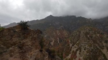 American Fork Canyon 'da kasvetli bir günde uçurum kenarına doğru yürüyen kişi vadiyi seyrediyor..