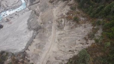 Toprak yol ve Marsyangdi nehri boyunca yürüyen insanlarla birlikte hava manzarası heyelana doğru uçuyor..