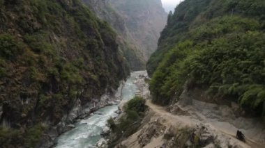Marsyangdi Nehri üzerinde kanyondan aşağı uçup Nepal 'deki kayalıklara giden toprak yolu izliyorlar..