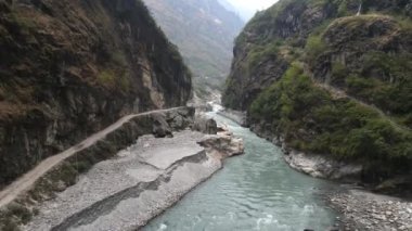 Marsyangdi Nehri 'nin üzerinden Annapurna Dağları' ndaki kayalıklardan geçen toprak bir yol ile kanyon boyunca uçuyor..