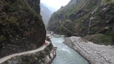 Araçlar Marsyangdi nehri boyunca dar uçurum yolunda ilerliyor. Nepal 'in vahşi doğasında dağın eteklerine doğru gidiyorlar..