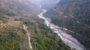 Annapurna Dağları 'ndaki Marsyangdi Nehri boyunca uzanan dağ vadisini kesen hava manzaralı toprak yol..