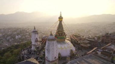 Aerial view circling around Swayambhunath Stupa in Nepal as people and monkeys wander around.