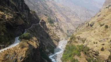 Marsyangdi Nehri 'nin üzerinden uçup dağın içine oyulmuş yolun yanındaki kanyondan geçeceğiz..