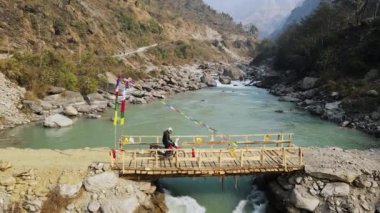 Manang Nepal yakınlarındaki Marsyangdi Nehri 'nden motorsikletle geçen kişi..