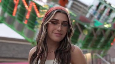 Karnavalda gülümseyen ve poz veren genç bir kadın gözlüklerini düzeltirken.