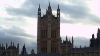 Londra'daki Westminster Sarayı kulelerinin gözde silik manzarası. Kamera soldan sağa kayar. Bazı bulutlar ile Gökyüzü arka plan oluşturur.
