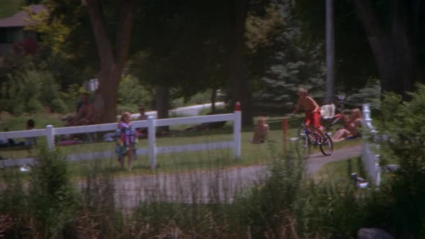 ドックから湖に自転車に乗っている少年のパンニング スローモーションショット カメラは彼を追いかけ 斜面から離れた — ストック動画