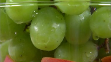 Bir tilt nektarin ve beyaz ekranda dönen bir vazo içinde üzüm kadar.