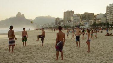 Rio De Janeiro-Haziran16, 2013: Ipanema plajında bir futbol etrafında geçen gençlerin yavaş hareket tava. Gruptan biri, genç bir adam, bisiklet çerçeve dışında topu tekmeler. Rio de Janeiro, Brezilya'da çekildi.