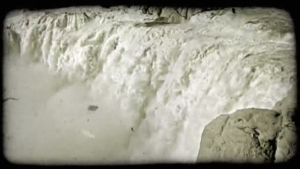 空気中にミストを噴霧流れ落ちる水と壮大な滝を形成する渓谷の端にある崖を壊すの荒れ狂う川水の右に左に ビンテージの様式化されたビデオ クリップ — ストック動画