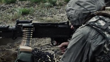 Bir askerin oturma pozisyonundan kemerle beslenen makineli tüfeği ateşlediği vuruldu. Mermi zinciri silah geçer ve kartuş ve kemer parçaları diğer taraftan dışarı atılır. Yeşil Bereli Abd Ordusu Özel Kuvvetler için bir eğitim gönderen.