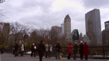 New York'taki Central Park'taki buz pateni pistinde izleyenlerin izini sürüyoruz. Cityscape arka planda görünür.