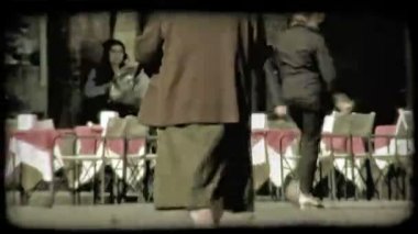 Yaşlı bir kadın kahverengi ceketli bir İtalyan plaza yürüyor. Vintage stilize video klip.
