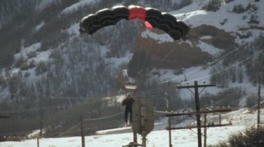 Bu yavaş çekim, karlı bir kayak pistinde iniş için gelen bir baz jumper, kayak giyen. O biraz teeters ama bu ayakları üzerinde kalmayı başarıyor.