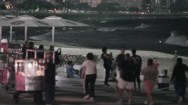 ジャネイロ 2013 露店の静的なショットを閉じて Copacobana 上の歩行者は 夜ビーチします 屋台は 歩道でカートを押しています バック グラウンドで市が点灯します — ストック動画