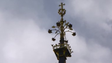 Londra'da Big Ben saat kulesi parçası extreme sabit yakın çekim. Altın süsler ve küçük bir haç görülebilir. Mavi gökyüzü ve geçen bazı bulutlarla çevrili.