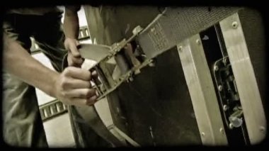Levis ve yeşil t-shirt giymiş genç adam bir kamyon içinde stabilize gibi bu büyük sandık gider ağır kemer sıkılaştırır. Vintage stilize video klip.