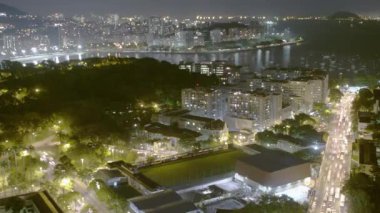 Rio de Janeiro, Brezilya'da işlek caddeleri bakan gece hızlandırılmış. Yeşil tepenin panoramik manzarası, büyük binaların yer verdiği şehir manzarası ve arka planda okyanus.