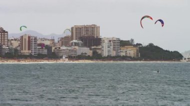 Atış üç görünür paraşüt sörfçü kaydırma. Copacabana Plajı ve şehir arka planda vardır. Şehrin gökdelenler oluşur. Dağlar puslu ama cityscape ötesinde görünür. Rio'da filme.