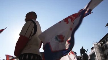 Bayrak tutan şık kıyafetleri giymiş erkekler bakarak orta vurdu