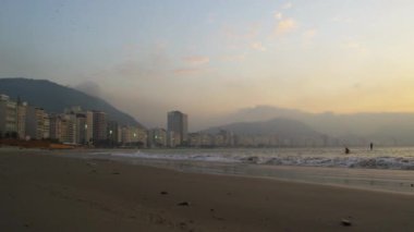 Pan Rio de Janeiro sahil günbatımında çekilen Brezilya. Bir kanocu ve raket Pano sörfçü denizde görülür.