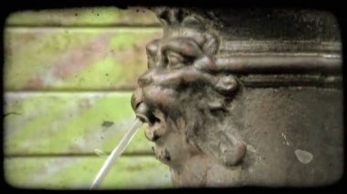 Bir kadeh bir çeşme için bir emzik gibi davranan bir taş kafa. Vintage stilize video klip.