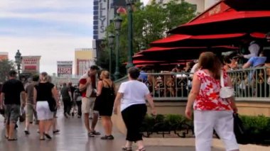 Timelapse yakınlaştırma raslantı giyimli turist Throngs Las Vegas Strip ve bir restoran sağa şemsiyelerle sel.