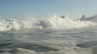 Dalgalar sahil Rio de Janeiro kapalı. Kamera bir statik bir duvar beyaz dalga yuttu olmak kadar savaşabilir ve lens koyu olur.