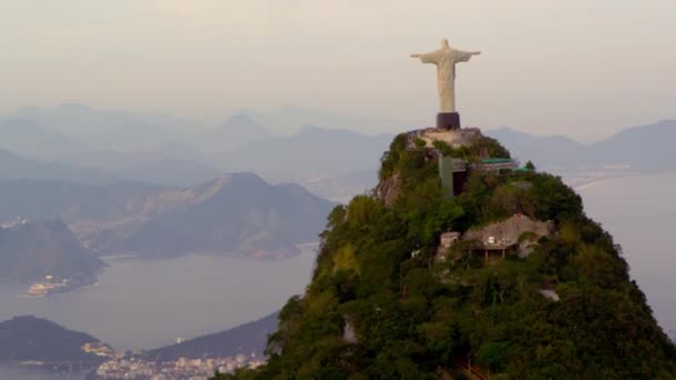 ジャネイロ ブラジル グアナバラ湾を見下ろすコルコバード山と周囲の山の上に立つキリスト Redentor 像の空中追跡映像 観光客が見落とす点像の近くで混雑しています — ストック動画
