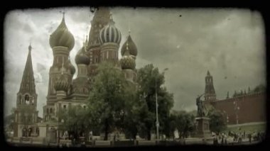 Pan St. Basil's Katedrali üzerinde insanlar ve Moskova, Rusya Red Square yakınındaki arka planda bulutlu gökyüzü ile ağaçların yanında aşağıda keşfetmek turist Kremlin Saat Kulesi için. Vintage stilize video klip.