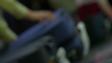 İnsanlar eşyalara uzanır ve onları taşırken çantalar bagaj talebinin etrafında dolaşır..
