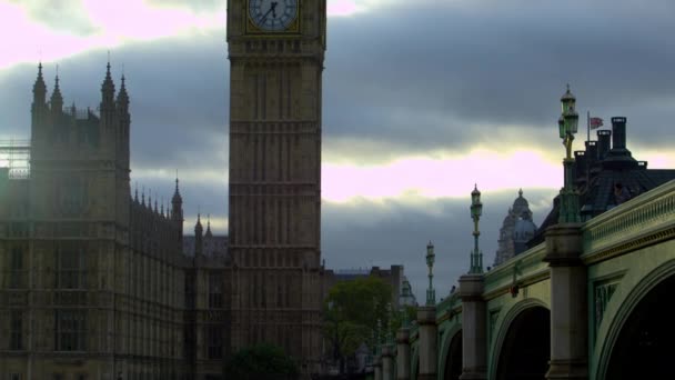 カメラはロンドンのビッグベン時計塔で徐々に上向きに動きます ウェストミンスター宮殿と橋のビットも見える — ストック動画