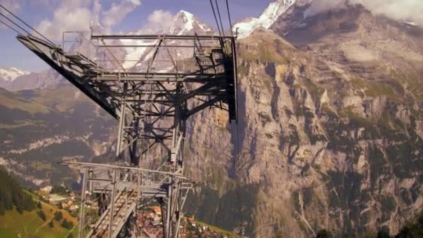 スイス アルプスの麓の村の空中ショットを追跡します ショットは ビデオ撮影は 山から下りて 街並みや松の木を示しています — ストック動画