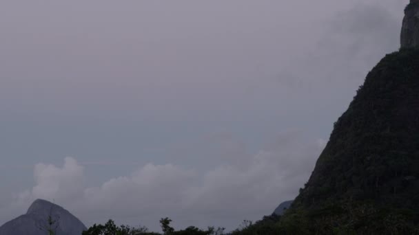 基督在高于巴西里约热内卢的科尔科瓦多向上平移镜头 摄影机镜头移权和山上直到这座雕像是在上部左上角的框架 天空被阴云塞满 — 图库视频影像