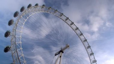 London Eye Londra, İngiltere'de arka planda mavi bulutlu gökyüzü ile düşük açılı görünümü.