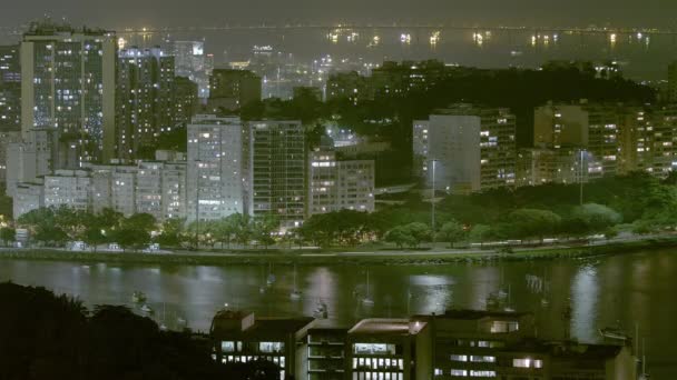 ブラジル リオデジャネイロの小さな半島の海岸沿いの多くの建物と道路を示す夜間の空中時間の経過 — ストック動画
