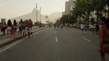 Rio De Janeiro, Brezilya - 24 Haziran 2013: yavaş hareket izleme çekim bir Brezilyalı kız paten Avenida Vieira Souto, bir grup Brezilyalı arkadaşıyla cadde boyunca yürüyüş yaptı kamera tava aşağı