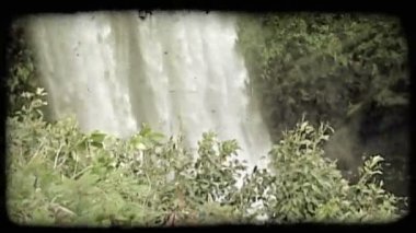 Yüksek şelale havuz aşağıdaki tüm sahne ve kayalık bir Hawaii Adası duvara şelale closeup üzerinden yavaş zum dışarı. Vintage stilize video klip.