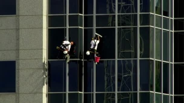 メンテナンスふたりは晴れた日にソルトレイクシティ ユタ州に超高層ビルの側面からぶら下がっている間一斉に Windows を洗う — ストック動画