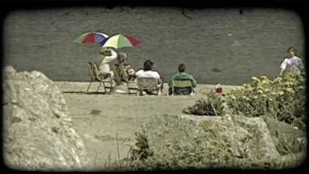 Casal Mais Velho Sentado Cadeiras Praia Sob Guarda Chuvas Coloridos — Vídeo de Stock