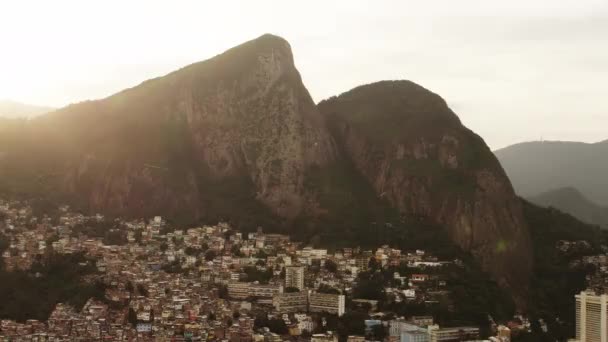 都市と山間の崖の空中映像 崖の後ろから太陽の光が輝いています ジャネイロで撮影 — ストック動画
